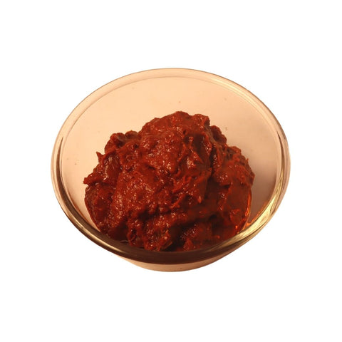 A traditional Indian condiment, tomato pickle, exhibiting a mix of savory spices and tomato chunks.